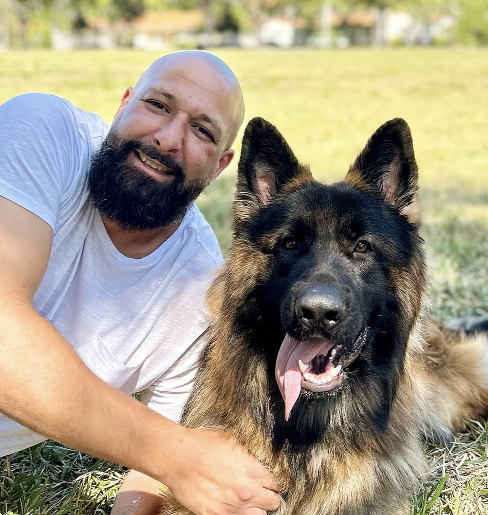 Uncle Jess smiling beside a German Shepherd he trained, in a sunny Florida field
